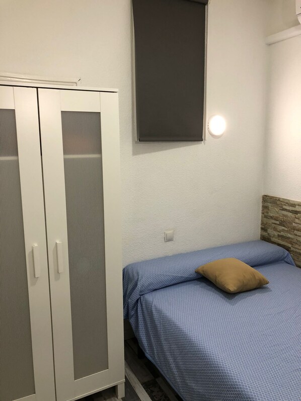 A bedroom with a bed, a wardrobe, and a wall-mounted light fixture. - H Noche y Dia (Madrid)