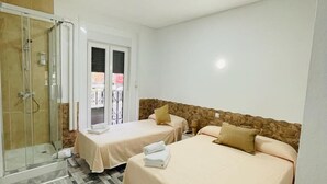 Habitación de hotel con dos camas, zona de ducha y suelo estampado.