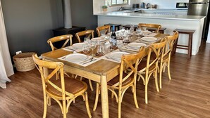 A dining area with a wooden table set for six, surrounded by six wooden chairs with woven seats. - Bass River Farm 9 mins from Phillip Island (Bass)