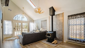 A spacious living room with a large sofa, a fireplace, and a chandelier. - BRAND NEW HOT TUB-SAUNA-2 WEBER GRILLS-FIRE PIT-AC-THERMOMIX (Long Pond)