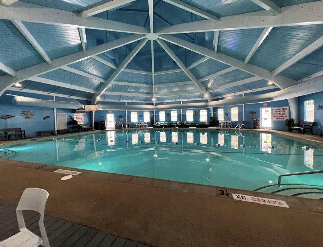An indoor swimming pool with a high ceiling and a clear water surface.