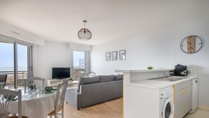 Een modern appartement met een eethoek, een bank, een keuken en een wasmachine.