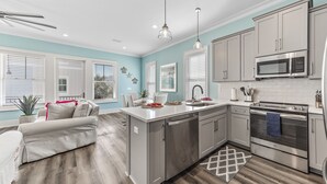 A modern kitchen with grey cabinets, stainless steel appliances, and a central island. - Steps to beach, BBQ, bikes, pool, arcade, Wifi (Gulf Shores)