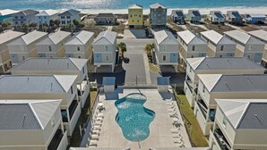 A resort with multiple buildings, a central swimming pool, and a beach view. - Steps to beach, BBQ, bikes, pool, arcade, Wifi (Gulf Shores)
