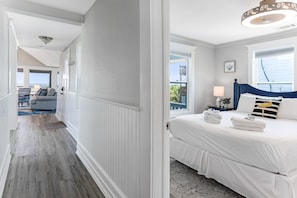 Ein Schlafzimmer mit Bett, Nachttisch, Lampe und Blick ins Freie.