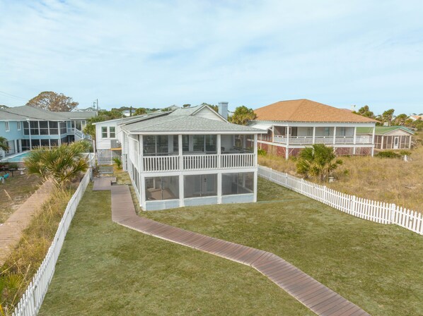 A two-story house with a covered porch and a fenced yard. - Our most Popular Rental on Tybee! Voted best view! by Tybee Cottages (Tybee Island)