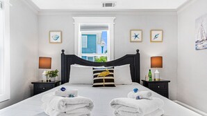 A hotel room with a large bed, two bedside tables, a window with a view, and artwork on the walls. - Our most Popular Rental on Tybee! Voted best view! by Tybee Cottages (Tybee Island)