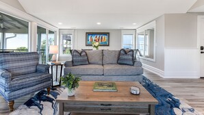 A living room with a sofa, coffee table, and a painting on the wall. - Our most Popular Rental on Tybee! Voted best view! by Tybee Cottages (Tybee Island)