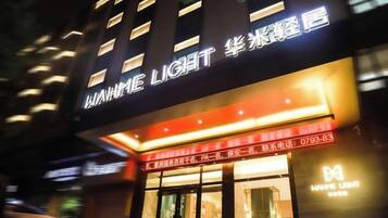 Un hotel con un cartello ben visibile che mostra il nome 'WAMME LIGHT' e un numero di telefono.