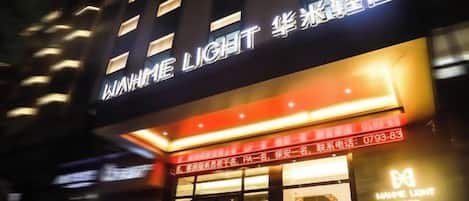 Un hotel con un cartel llamativo que muestra el nombre 'WAMME LIGHT' y un número de contacto.