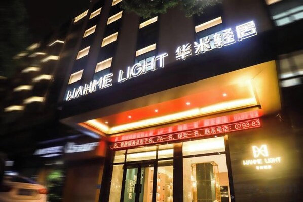 A hotel with a prominent sign displaying the name 'WAMME LIGHT' and a contact number.