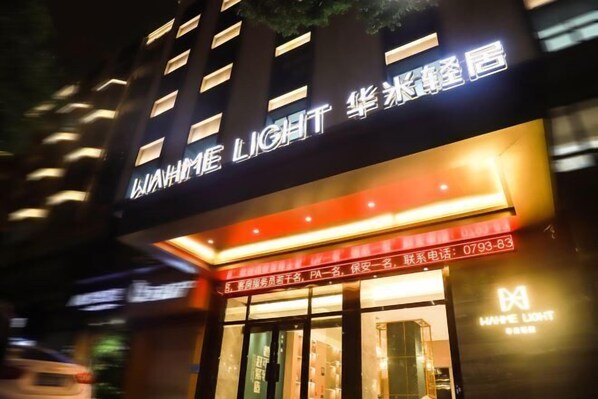 Un hotel con letreros iluminados y un toldo rojo.