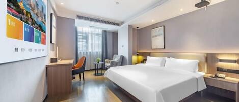 A hotel room with a large bed, a desk, a chair, and a small table.