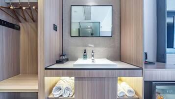 A modern bathroom with a wooden vanity, a mirror, and a built-in towel rack.