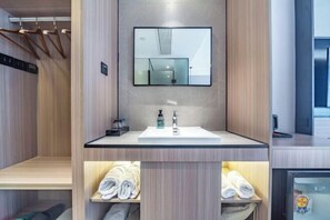 Un baño moderno con tocador de madera, un espejo y un toallero empotrado.