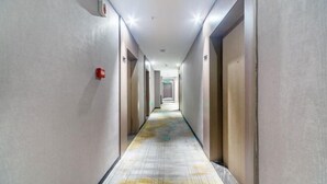 A long, narrow hallway with doors on both sides, leading to rooms. - Wahme Light Hotel (Shangrao)