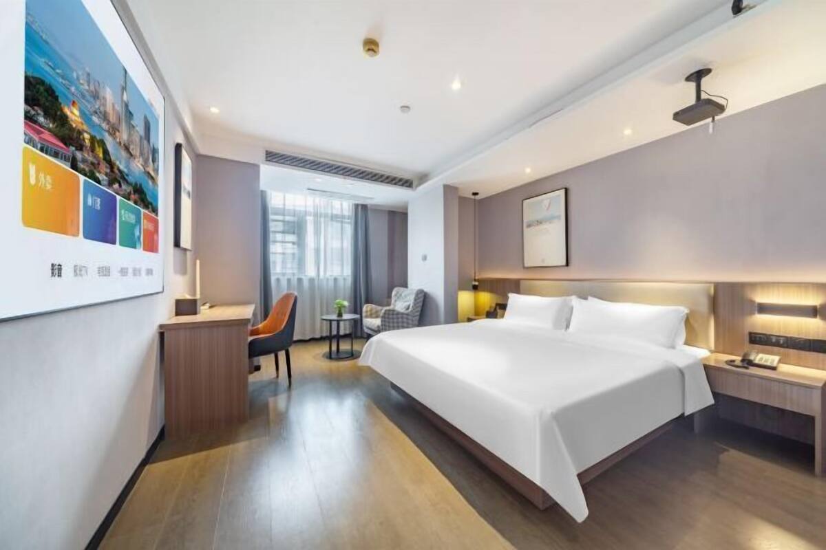 Une chambre d’hôtel moderne équipée d’un grand lit, d’un bureau, d’une chaise et d’une petite table.
