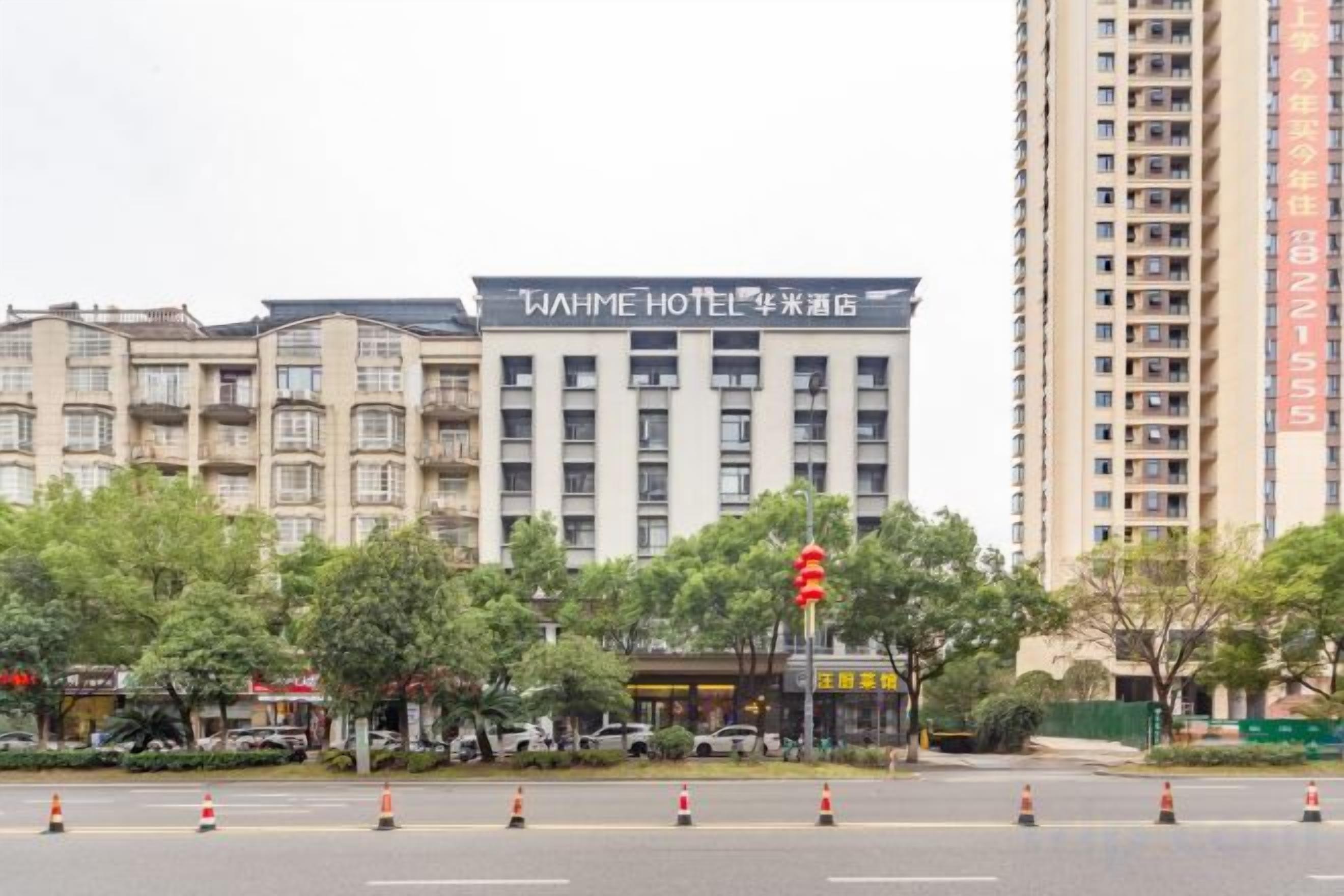 A multi-story hotel building with a prominent sign, surrounded by trees and traffic cones.