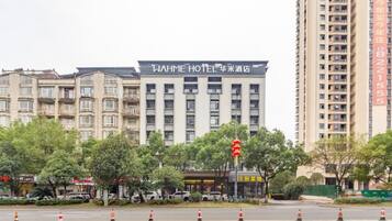 A multi-story hotel building with a prominent sign, surrounded by trees and traffic cones.