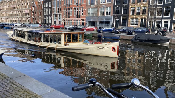 Ein Kanal mit einem Boot namens FLAGSHIP, umgeben von historischen Gebäuden mit traditioneller Architektur.