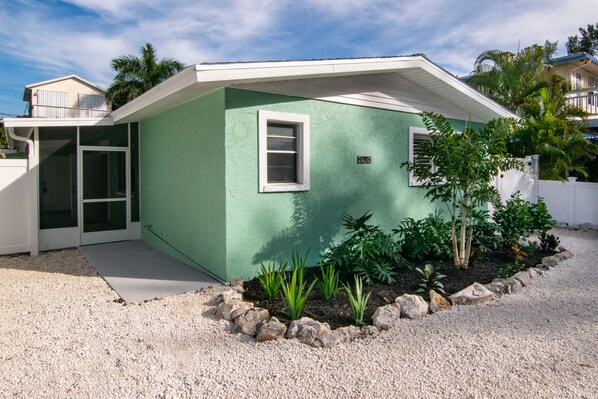 A single-story house with a green exterior, a white door, and a small window.