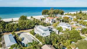 An aerial view of a coastal residential area with houses, a beach, and a clear view of the ocean. - Made In The Shade A &B | Multiple Units (Holmes Beach)