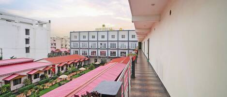 A corridor with a balcony, a row of buildings with red roofs, and a clear sky.