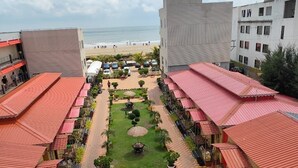 Une cour d’hôtel avec des espaces de repos en plein air, une pelouse centrale et une vue sur la plage.
