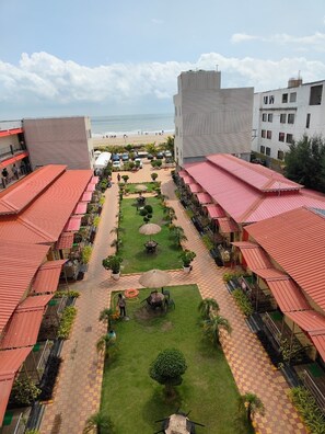 A hotel courtyard with outdoor seating, a central lawn, and a view of the beach.