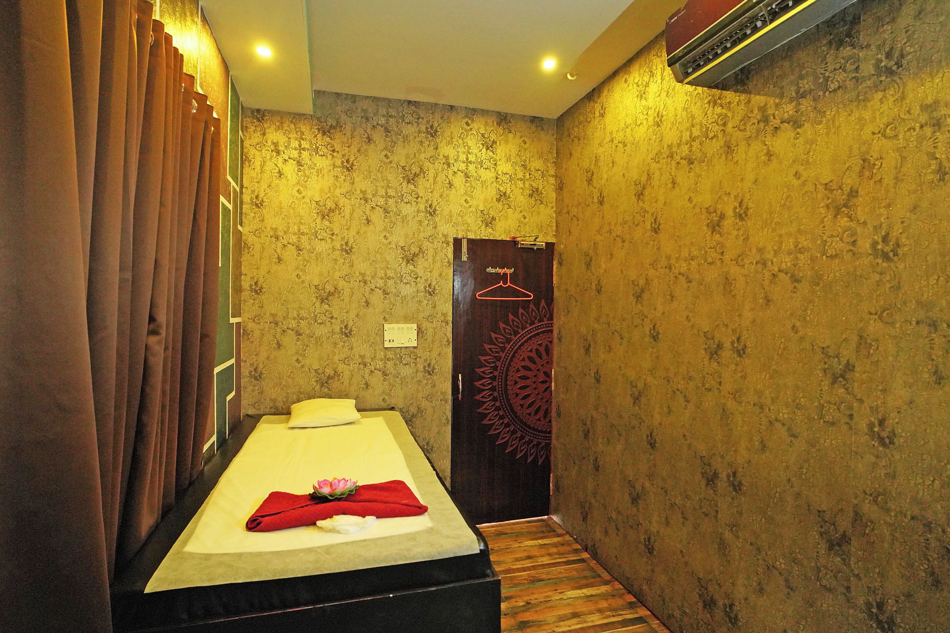A room with a bed, curtains, a door with a hanger, and patterned wallpaper.
