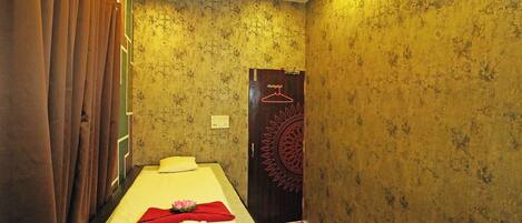 A room with a bed, curtains, a door with a hanger, and patterned wallpaper.