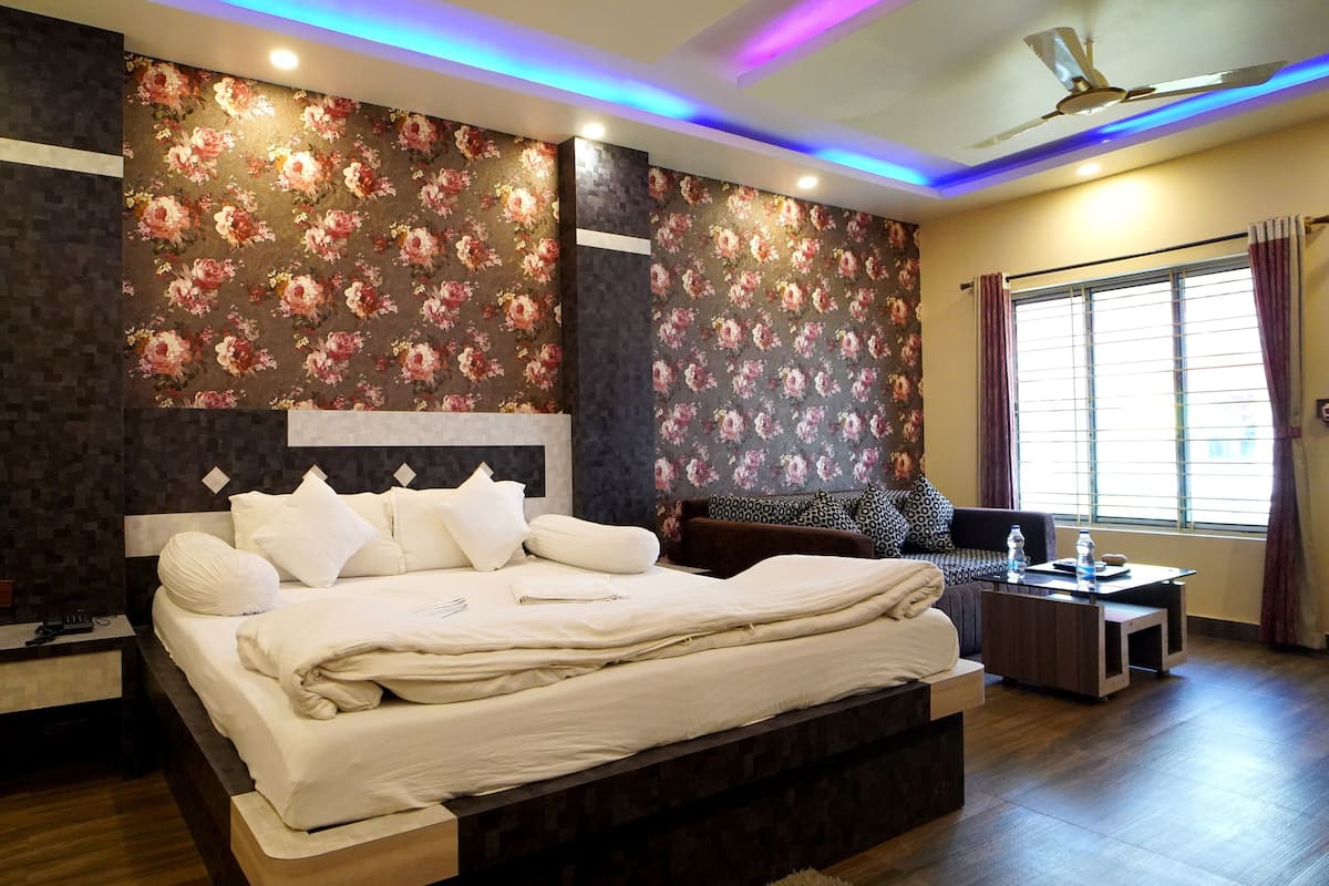 A modern bedroom with a large bed, a nightstand, a dresser, and a window with curtains.