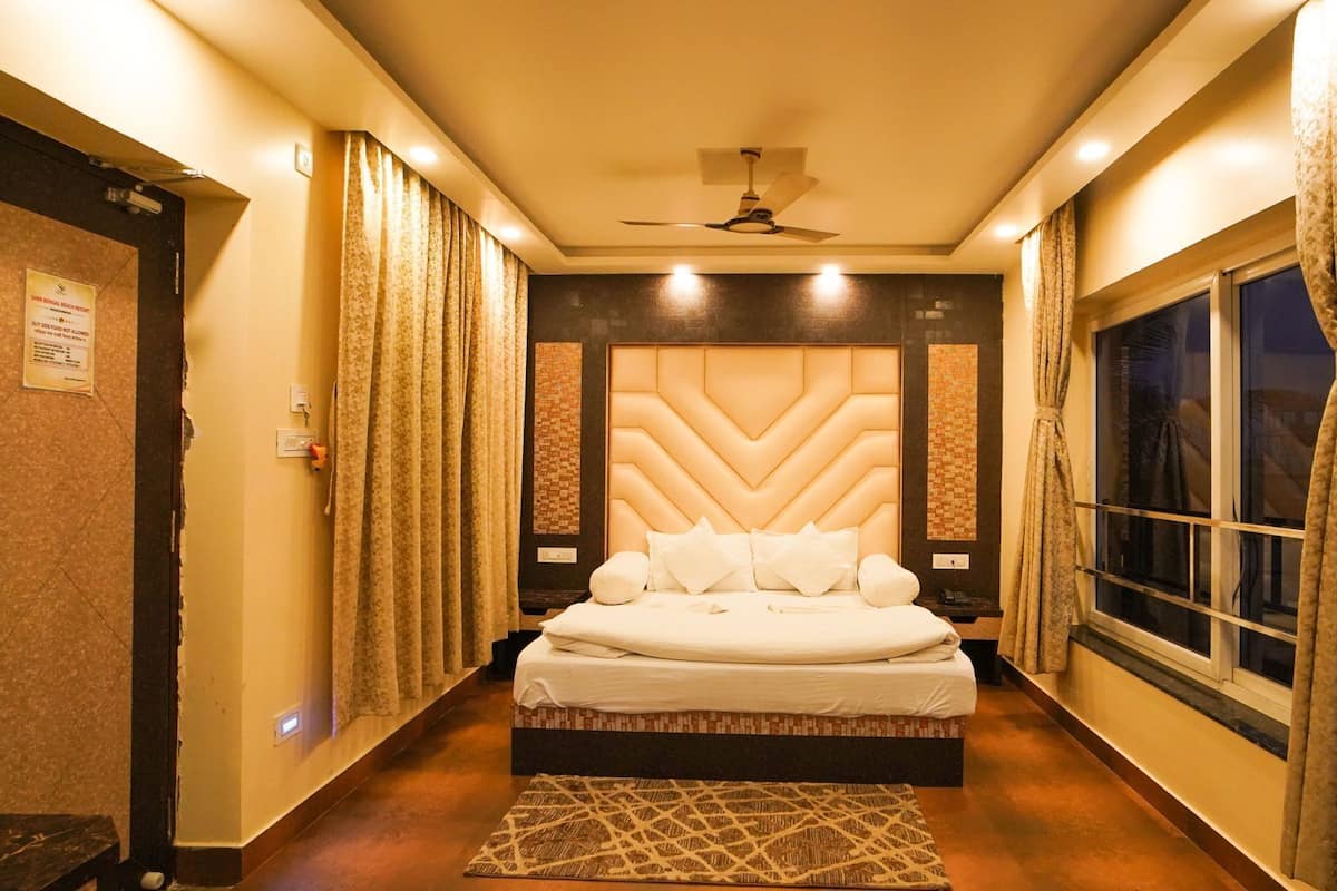 A hotel room with a large bed, a ceiling fan, and a window with curtains.
