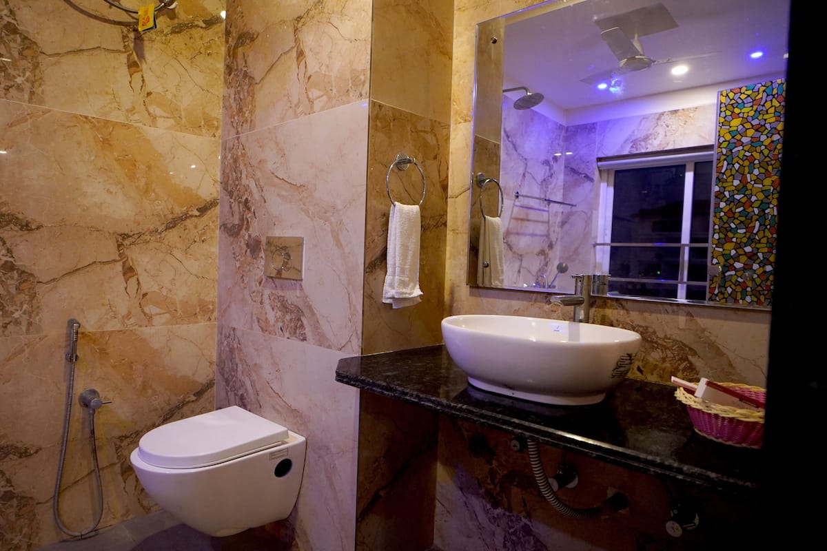 A bathroom with a marble wall, a toilet, a sink, and a shower.