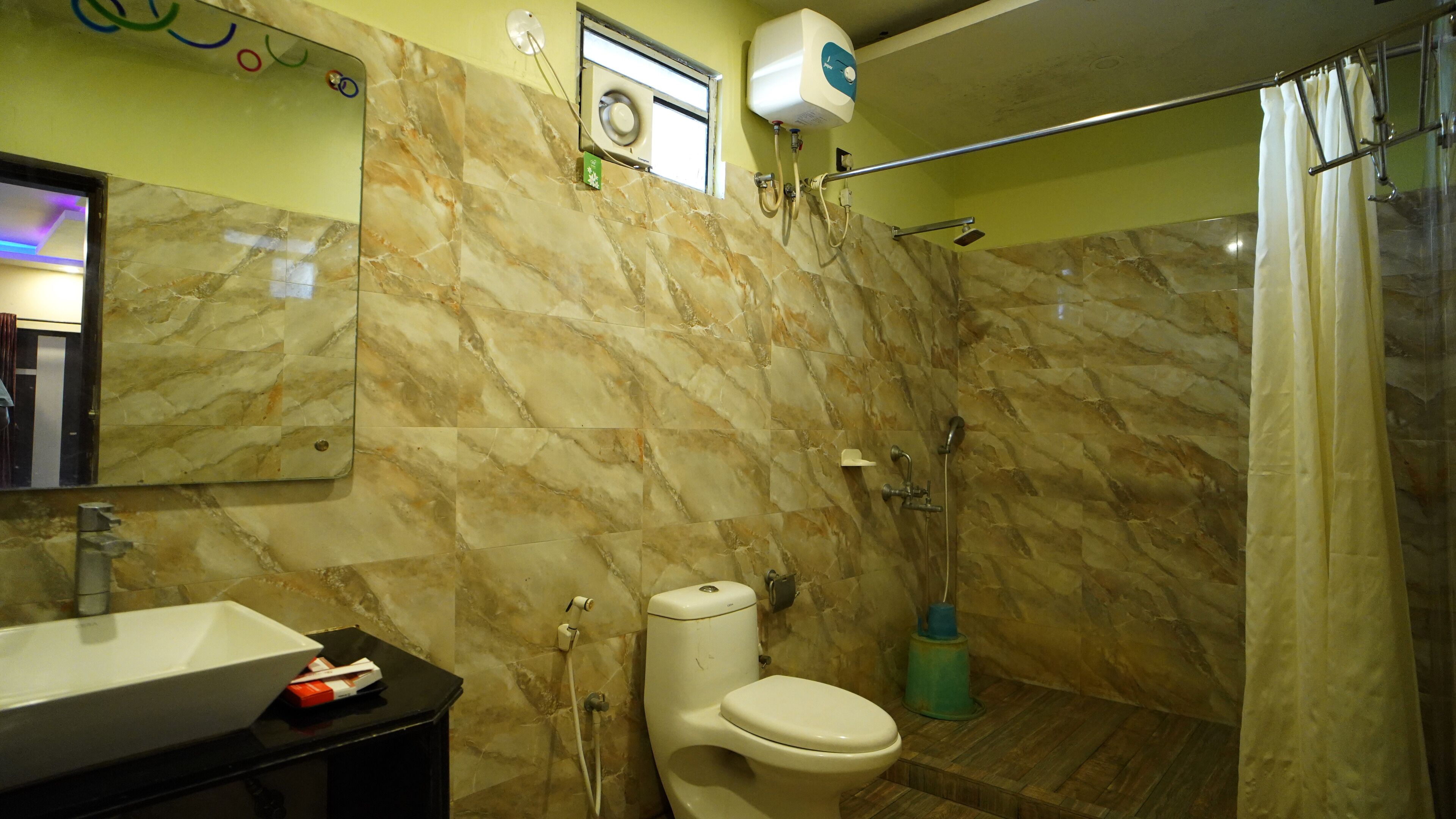 A bathroom with a marble wall, a toilet, a sink, and a shower area.