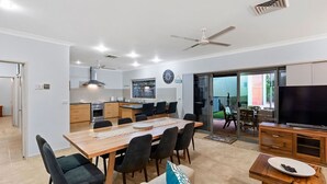 A modern kitchen with a dining area, a TV, and a balcony with outdoor furniture.