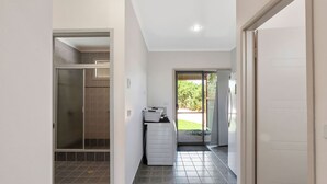 A hallway with a glass shower door, a laundry area with a washing machine, and a door leading to a garden.