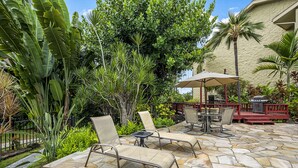 An outdoor patio with stone flooring, lounge chairs, and a small table. - Kalani Kai#109 1st Floor, Remodeled Unit in Heart of Kona Town! Best location (Kailua Kona)