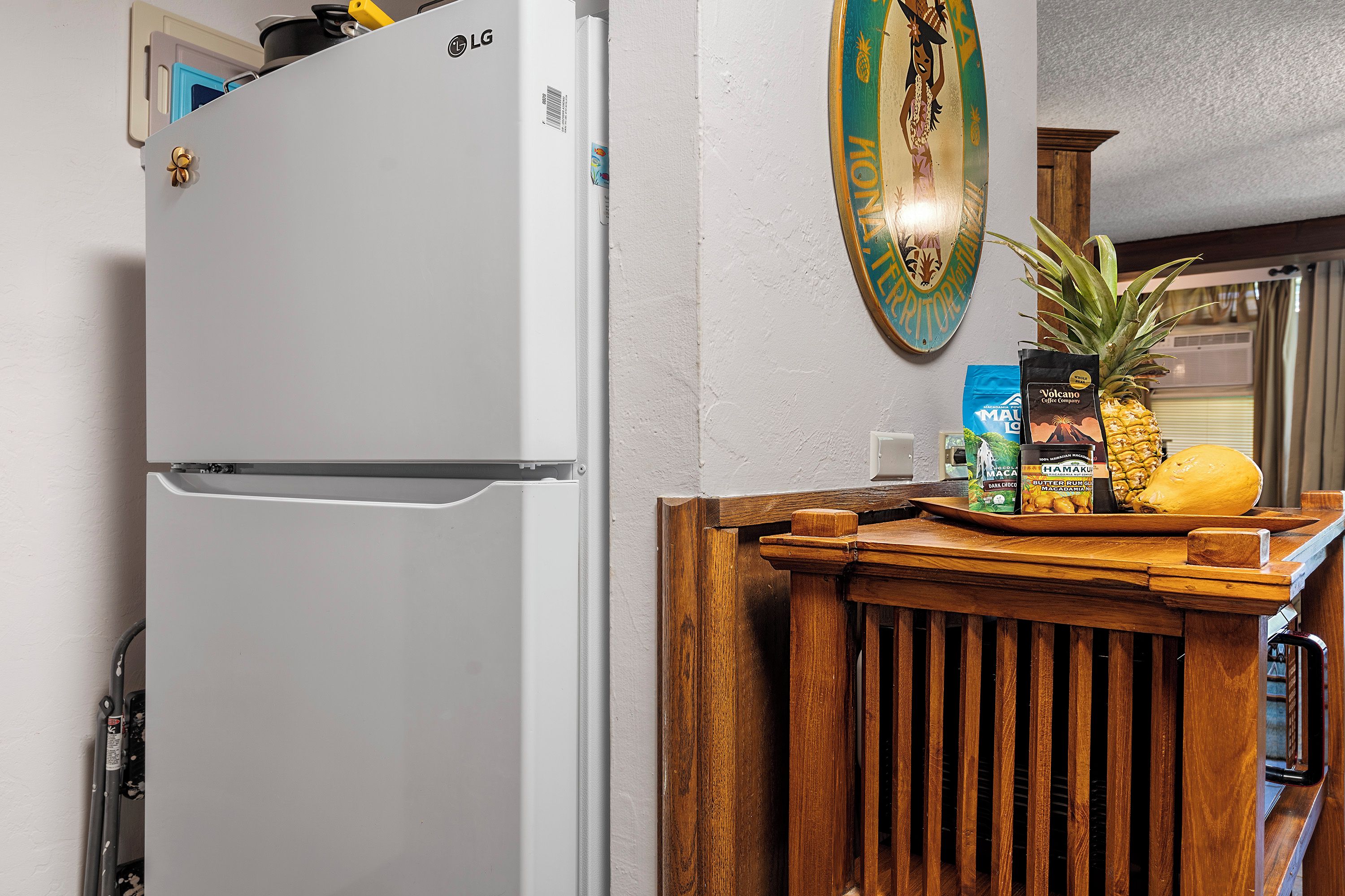 A kitchen with a white refrigerator, wooden counter, and a decorative plate on the wall.