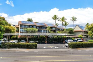 Un hôtel doté d’un parking couvert, de panneaux solaires sur le toit et de palmiers.
