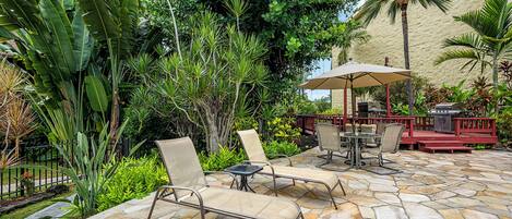 Une terrasse extérieure avec un sol en pierre, des fauteuils et une petite table.
