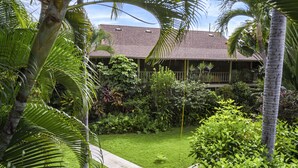 A lush garden with a pathway leading to a building with a tiled roof. - Kalani Kai#109 1st Floor, Remodeled Unit in Heart of Kona Town! Best location (Kailua Kona)