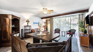 A dining area with a wooden table, benches, and a ceiling fan. - Kalani Kai#109 1st Floor, Remodeled Unit in Heart of Kona Town! Best location (Kailua Kona)