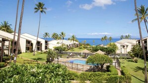 A resort with multiple buildings, a swimming pool, and palm trees.