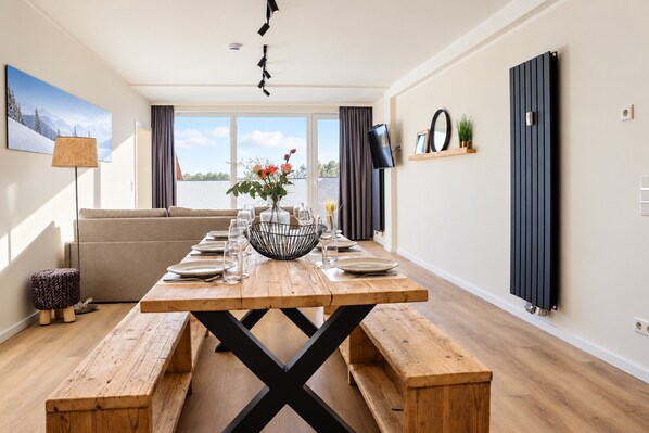 A dining area with a wooden table, benches, and a view of the outdoors.