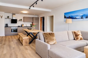 A modern living space with a sofa, a dining table, and a kitchen area.