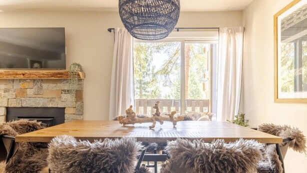 Un comedor con chimenea de piedra, una mesa grande de madera y sillas cubiertas de piel.