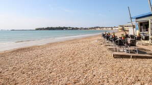 Une plage de galets avec un café et des tables en plein air.