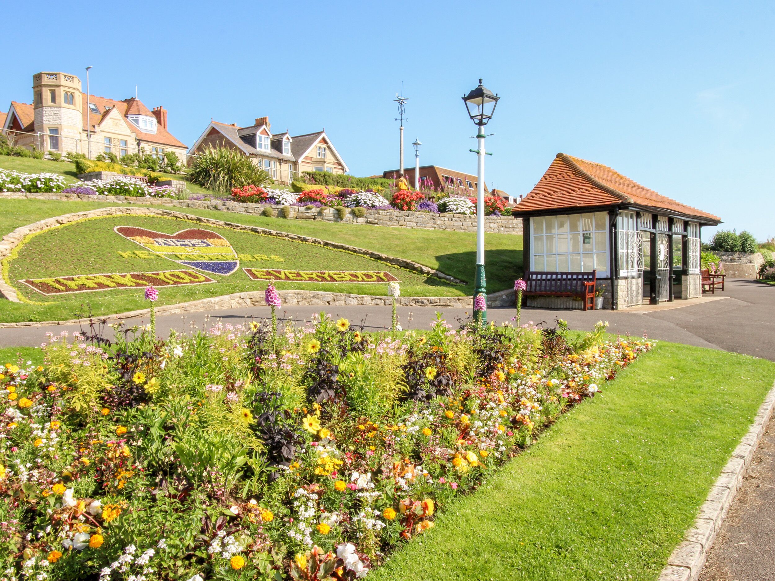 A well-maintained garden with a variety of flowers and a heart-shaped flower bed spelling out "EVERYBODY".