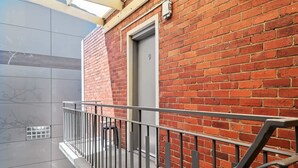 A balcony with a metal railing, a red brick wall, and a door with the number 9.